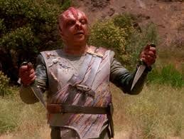 Captain Dathon presenting a dagger to Jean-Luc Picard on El-Adrel IV.