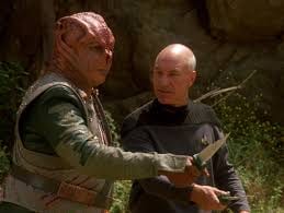 Captain Dathon standing outdoors on El-Adrel IV with both hands raised.