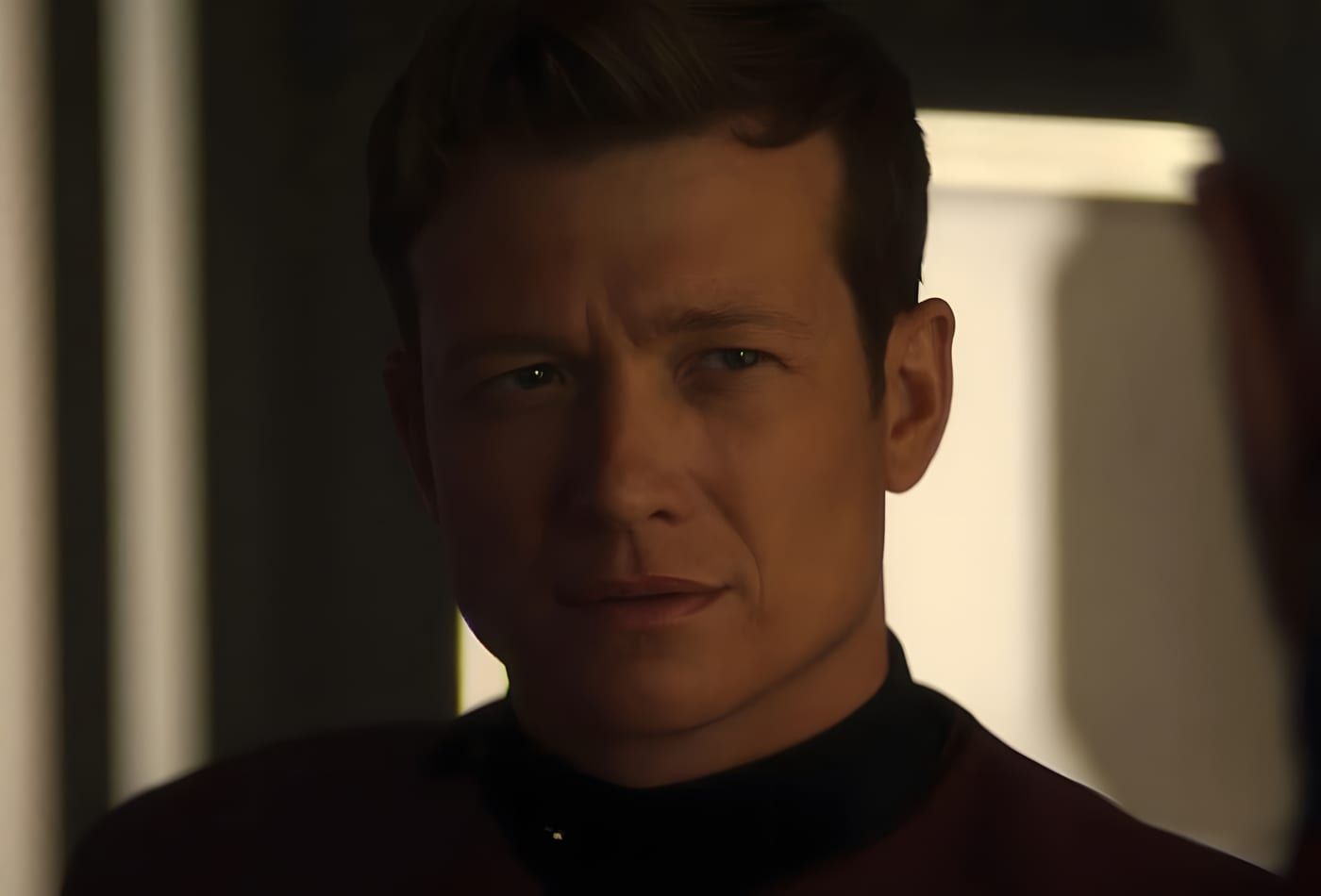 Jack Crusher in Starfleet duty attire, portrait with dramatic warm light on one side of his face, starship interior behind him.