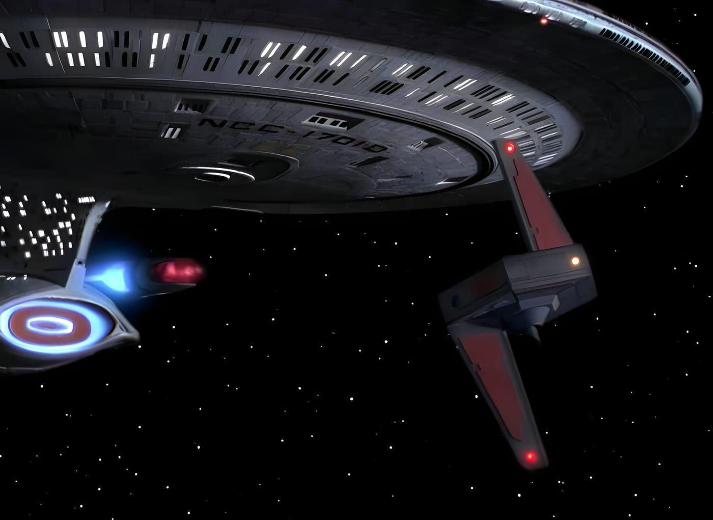 The Kataan probe alone in deep space: grey central body, vertical fins with reddish panels, a single yellow sensor glow.
