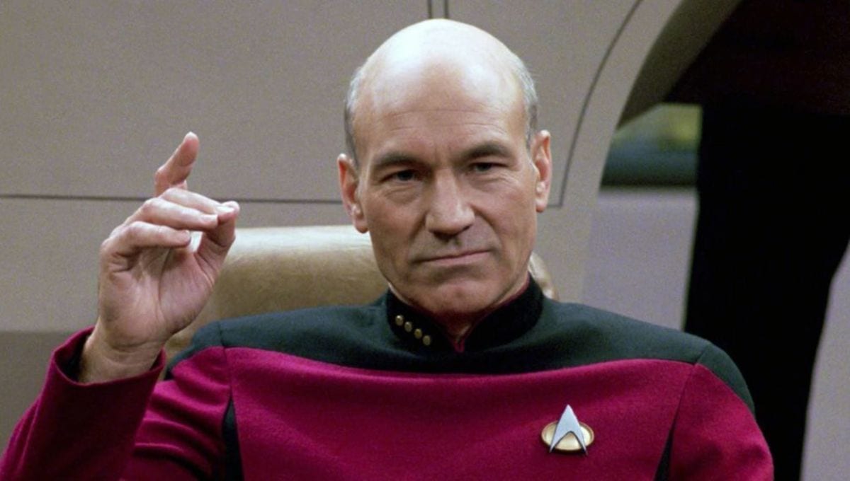 Captain Jean-Luc Picard in the Enterprise-D command chair, hand raised in a decisive gesture.