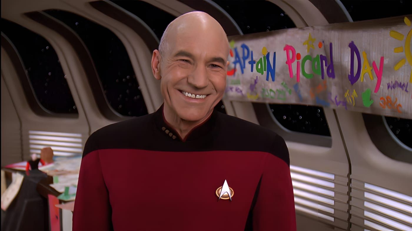 Captain Jean-Luc Picard in Starfleet command red, seated in the ready room with a thoughtful expression.