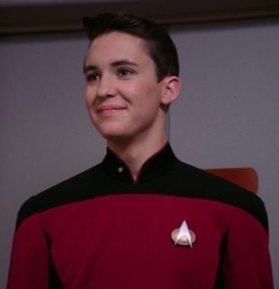Wesley Crusher in a red Starfleet uniform, smiling slightly.
